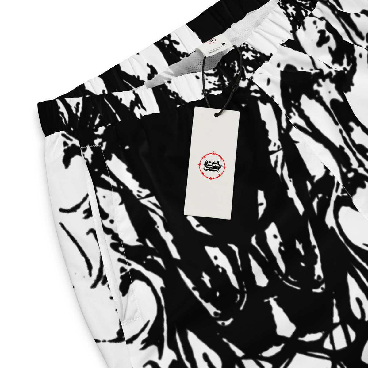 Black and white abstract patterned pants with an elastic waistband, featuring a white hangtag with a black and red logo.